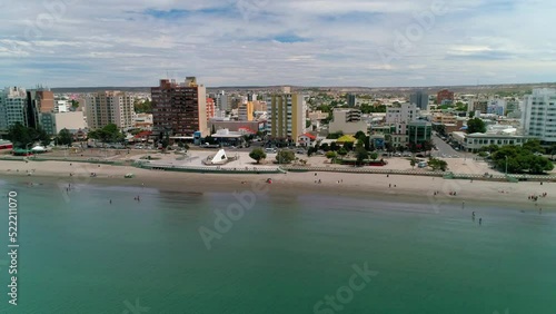 Aerial Shot Of Residential Buildings In City, Drone Flying Backwards Over Ocean - Puerto Madryn, Argentina photo