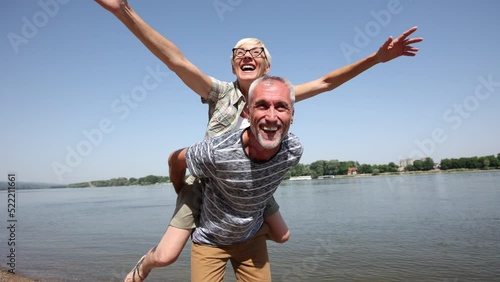 Portrait of happy mature man being embraced by his wife at the beach.