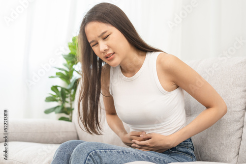 Flatulence asian young woman, girl hand in stomach ache, suffer from food poisoning, abdominal pain and colon problem, gastritis or diarrhoea. Patient belly, abdomen or inflammation, concept.