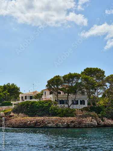 Fototapeta Naklejka Na Ścianę i Meble -  Villa by the sea behind the trees on the rocky coast, Ciutadella, Menorca, Spain