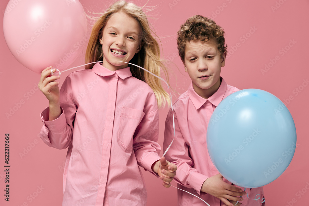 horizontal portrait of happy children in pink clothes playing with pink and blue balloons horizontal portrait of happy children in pink clothes playing with pink and blue balloons