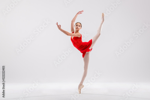 Beautiful young ballerina on a white background. The ballerina is dressed in a red leotard, pink leotards, pointe shoes.