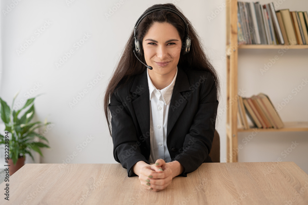 Serious call center operator in wireless headset talking with customer, woman in headphones with microphone consulting client in customer support service, looking at camera Serious call center operator in wireless headset talking with customer, woman in headphones with microphone consulting client in customer support service, looking at camera