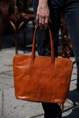 close-up photo of orange leather bag in a woman's hand