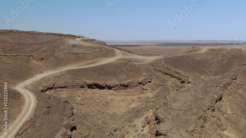 Dirt road over Gara Medouar mountain at Errachidia near Sijilmasa in Morocco, Africa. Aerial drone flyover photo