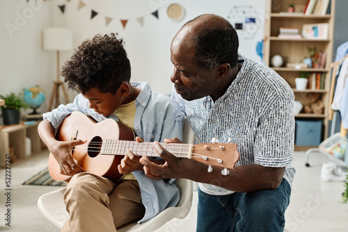 Fotografie, Obraz African boy having musical lesson with teacher at home, he teaching him to play