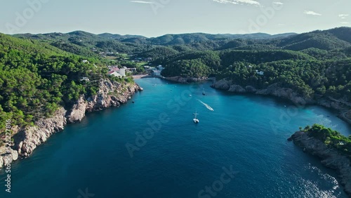 Scenic view from above of a beautiful paradise alike beach with green forest. Platja des Port de Sant Miquel with hotels, resorts and apartments in Ibiza, Balearic Islands, Spain. photo