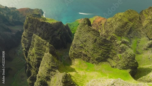 Cinematic aerial view of dramatic mountains and ocean on Napali Coast Kauai Hawaii. Aerial view flying over jungle mountain peaks revealing tropical coastline, Na Pali park Kauai. Adventure background photo