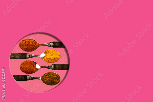 A selection of cayenne pepper tumeric chilli curry powder spices used in Indian cooking on a coulerful cerise pink background photo