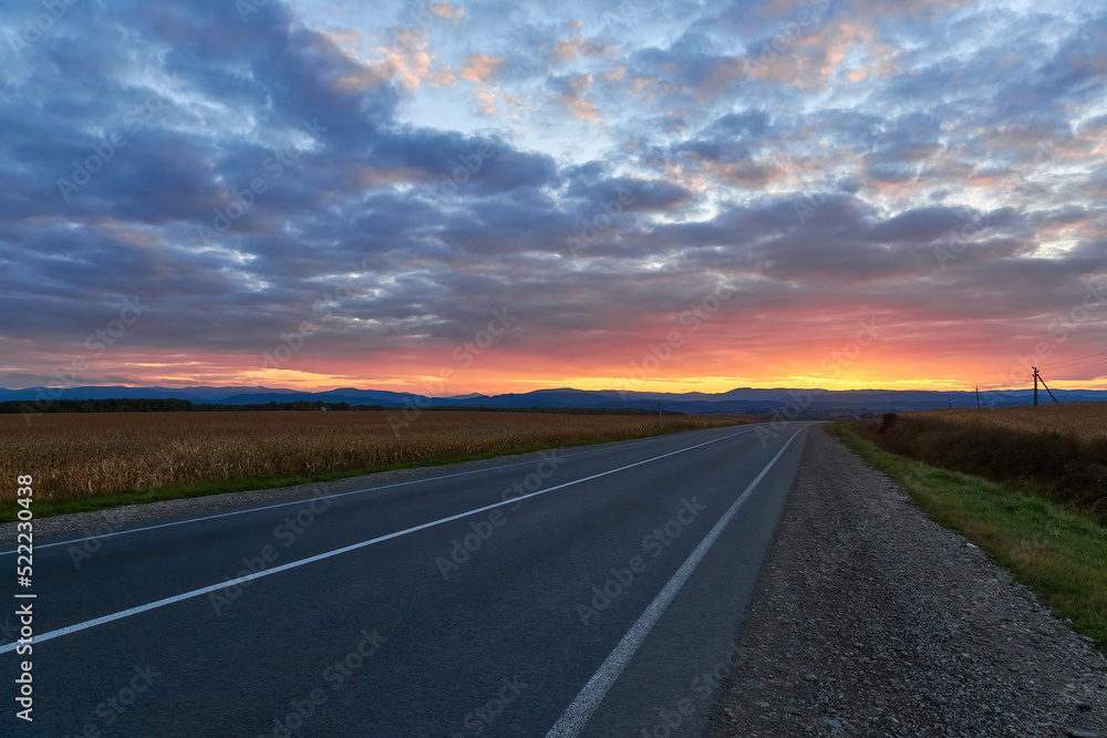 Asphalt road in motion with trees against a night sky with bright sunset Asphalt road in motion with trees against a night sky with bright sunset