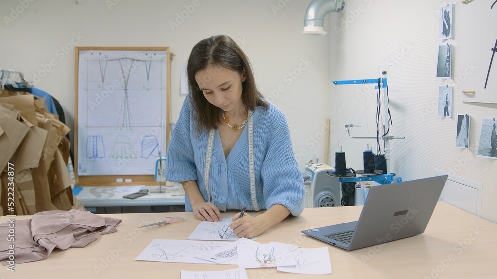 4K. A young woman working in a clothing store. A fashion designer makes sketches on paper. 4K. A young woman working in a clothing store. A fashion designer makes sketches on paper.