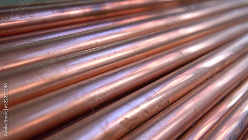 Metal, copper pipes stack with shiny reflections at warehouse. Plumbing, round tube sewerage products, manufacturing for building and construction, business production. Close up pan.
