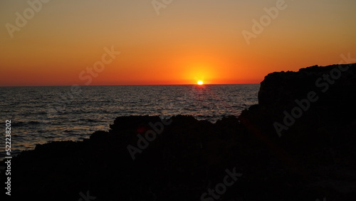 romantic sunset on the coast of Sardinia in Italy, with reddish and Mediterranean colors in the background with rocks on the coast