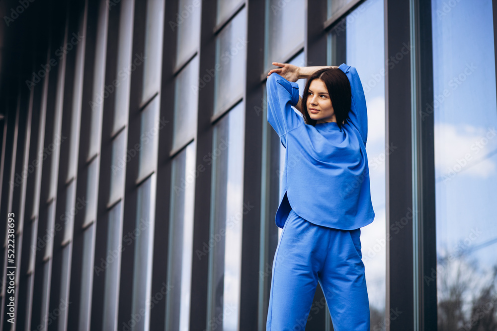 Woman in blue sports wear stretching outside the street Woman in blue sports wear stretching outside the street