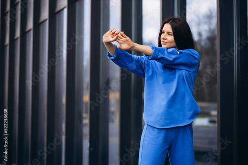 Woman in blue sports wear stretching outside the street