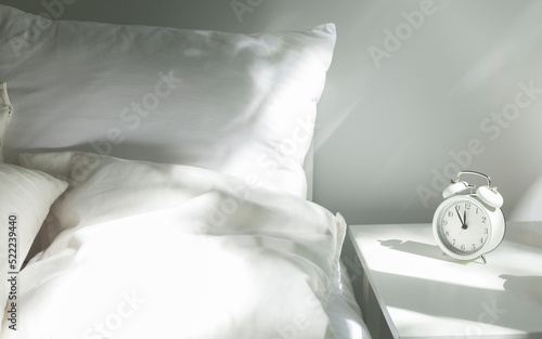 Foto a white alarm clock stands on the bedside table in the morning sun next to the m