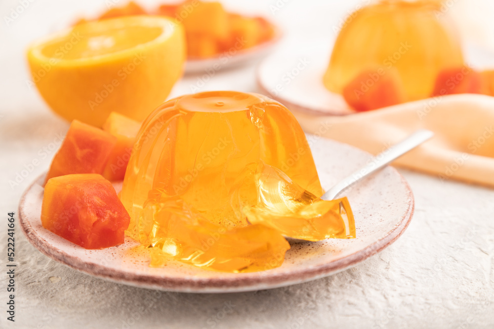 Papaya and orange jelly on gray concrete and orange linen textile. side view, selective focus. Papaya and orange jelly on gray concrete and orange linen textile. side view, selective focus.