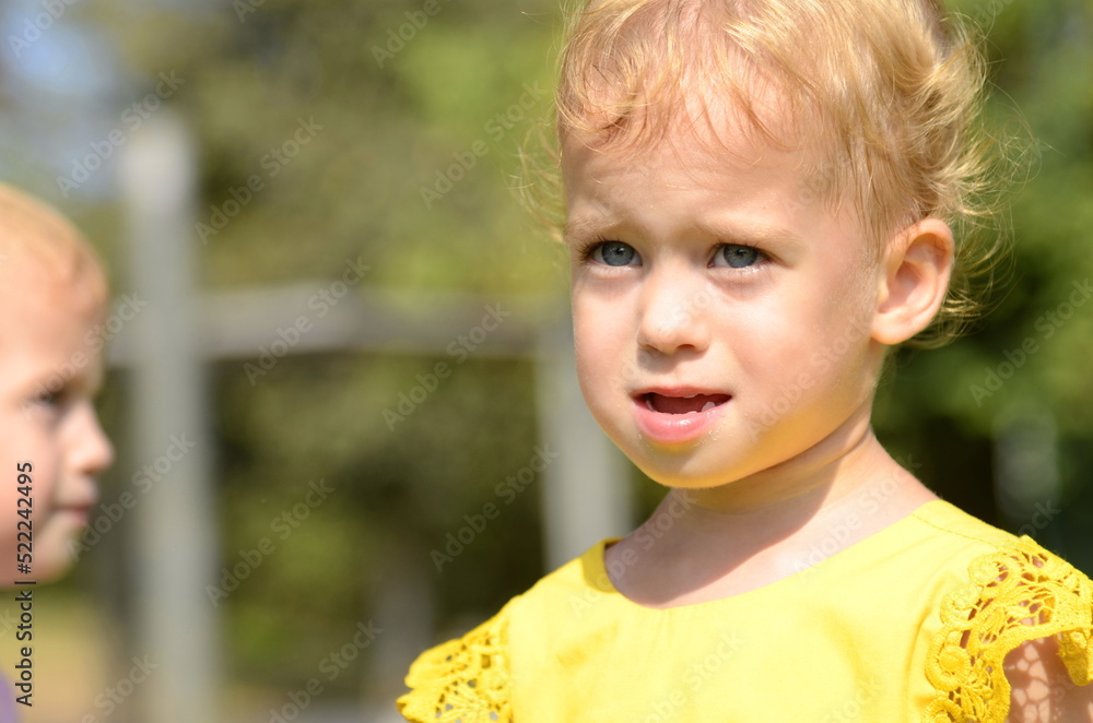 Portrait of a cute little girl in a yellow dress. Baby 2 years old. blond hair, blue eyes. Concept: happiness of motherhood, children's joy, kindergarten, children's health Portrait of a cute little girl in a yellow dress. Baby 2 years old. blond hair, blue eyes. Concept: happiness of motherhood, children's joy, kindergarten, children's health