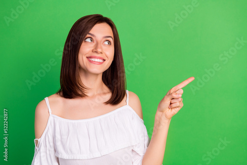 Photo of cheerful gorgeous lady toothy smile look indicate finger empty space isolated on green color background