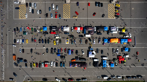 Colorful cars and people in a large parking lot as seen from above (aerial drone photo). Near Volokolamsk, Russia