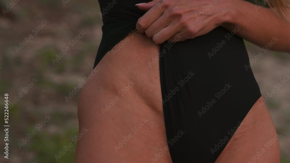 Fit young woman showing birth scar and stretches on her belly outdoors wearing a black body Fit young woman showing birth scar and stretches on her belly outdoors wearing a black body