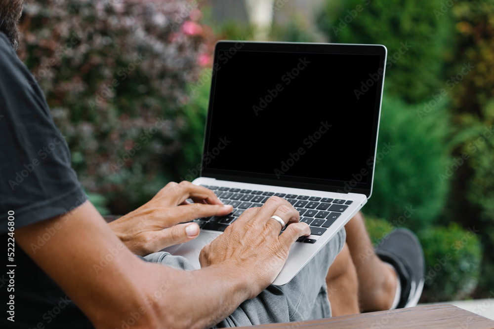 Fototapeta premium a man works in nature, sitting in a chair with a laptop