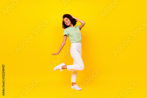 Full length photo of funny brunette lady dance wear t-shirt jeans shoes isolated on vivid yellow color background