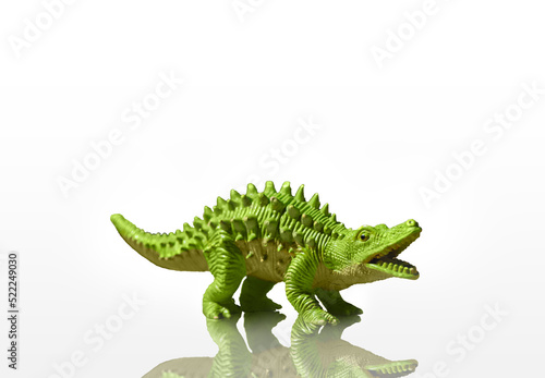 Figurine of a green dinosaur with spikes isolated on a white background with reflection added © Maksim