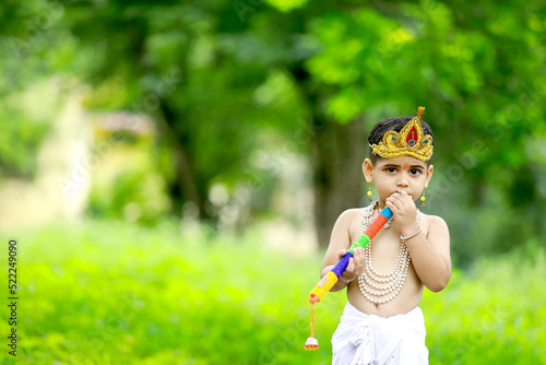 happy Janmashtami Greeting Card showing Little Indian boy posing as Shri krishna or kanha kanhaiya with Dahi Handi picture and colourful flowers