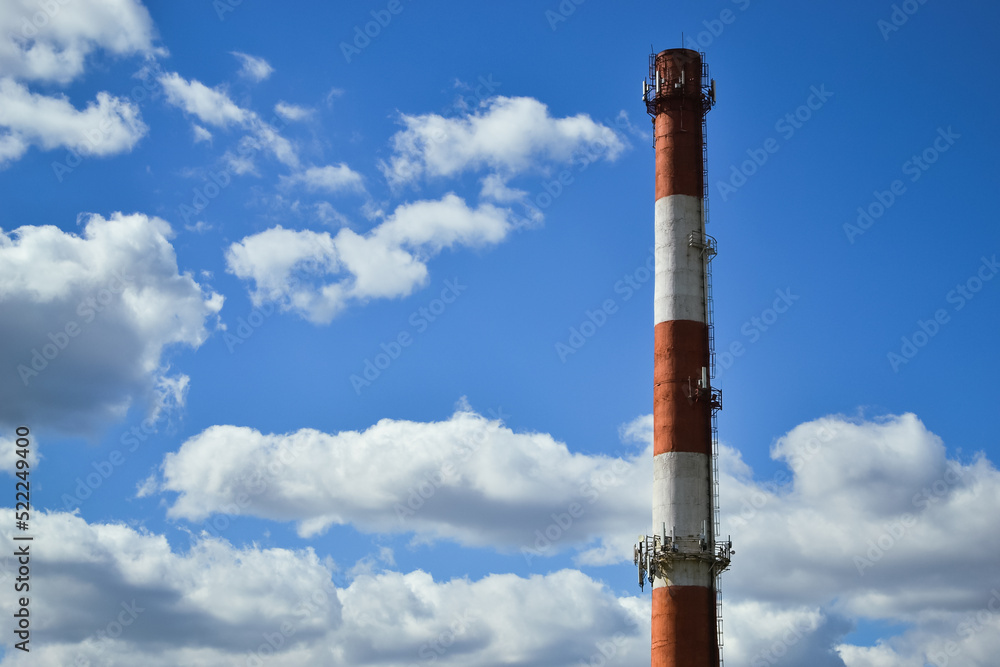 White and red boiler room chimney against the background of a beautiful blue sky and white clouds