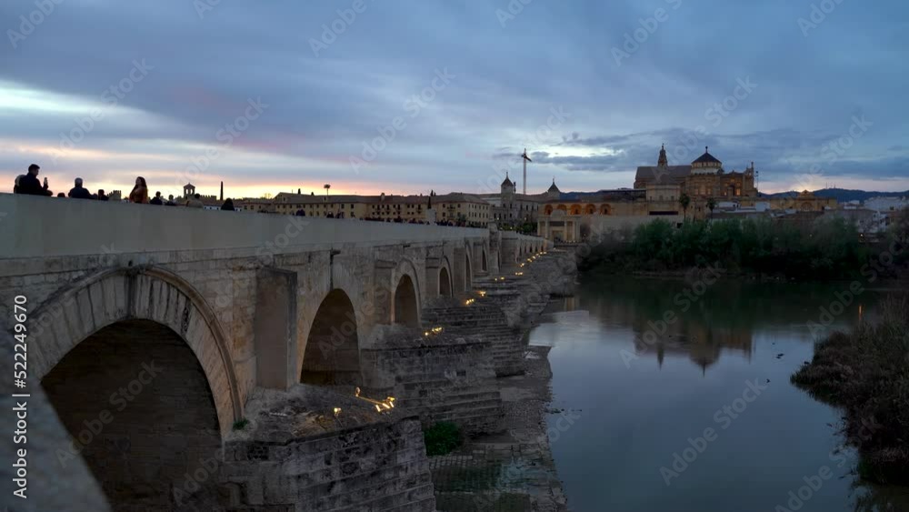 People walking over famous Roman Bridge in Cordoba, Spain during sunset People walking over famous Roman Bridge in Cordoba, Spain during sunset