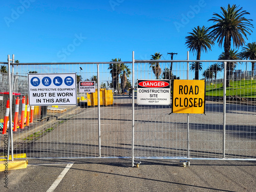 Construction site health and safety message rules signage on fence boundary - unauthorised persons keep out and protective equipment to be worn at all times.