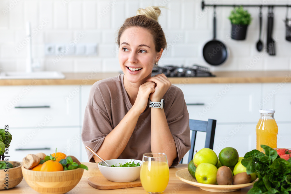 Healthy lifestyle, diet eating, weight loss concept. Young woman eating fresh salad while sitting in her kitchen. Beautiful happy female eats breakfast. vegetarian meal Healthy lifestyle, diet eating, weight loss concept. Young woman eating fresh salad while sitting in her kitchen. Beautiful happy female eats breakfast. vegetarian meal