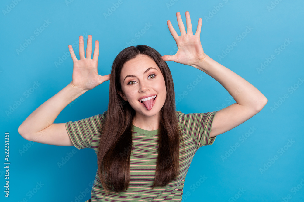 Photo of funky young brunette lady play wear striped t-shirt isolated on blue color background Photo of funky young brunette lady play wear striped t-shirt isolated on blue color background