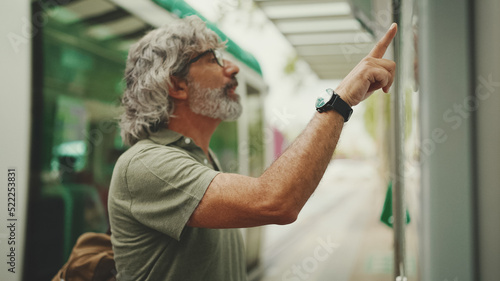 Wallpaper Mural Clouse-up, profile of middle-aged man with gray hair and beard, runs his finger along the city transport schedule. Mature gentleman in eyeglasses is waiting for tram Torontodigital.ca
