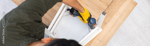 Wallpaper Mural Overhead view of young man repairing chair with electric screwdriver at home, banner Torontodigital.ca