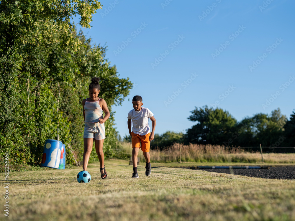 Obraz premium Siblings (8-9, 10-11) playing soccer