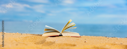 Buch am Strand mit blauem Meer im Hintergrund