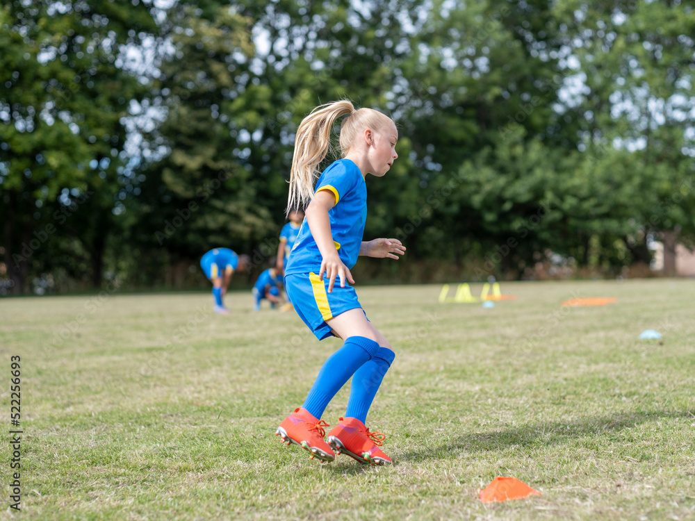 Girl (8-9) dressed in uniform practicing on soccer field Girl (8-9) dressed in uniform practicing on soccer field