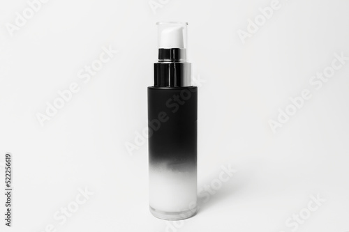 Close-up of dispenser bottle with body cream of black and white color, isolated on white background.