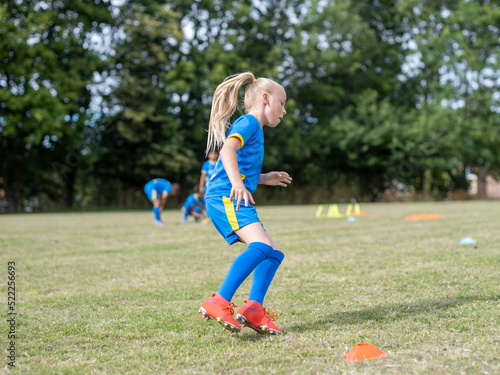 Girl (8-9) dressed in uniform practicing on soccer field