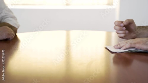 A man's hand pushes the envelope of money towards another man. He receives it and hides it. Men who give and receive bribes