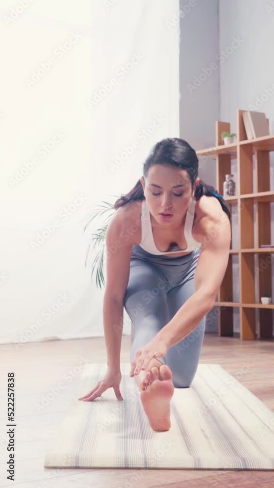 vertical video of young sportswoman stretching on fitness mat at home vertical video of young sportswoman stretching on fitness mat at home