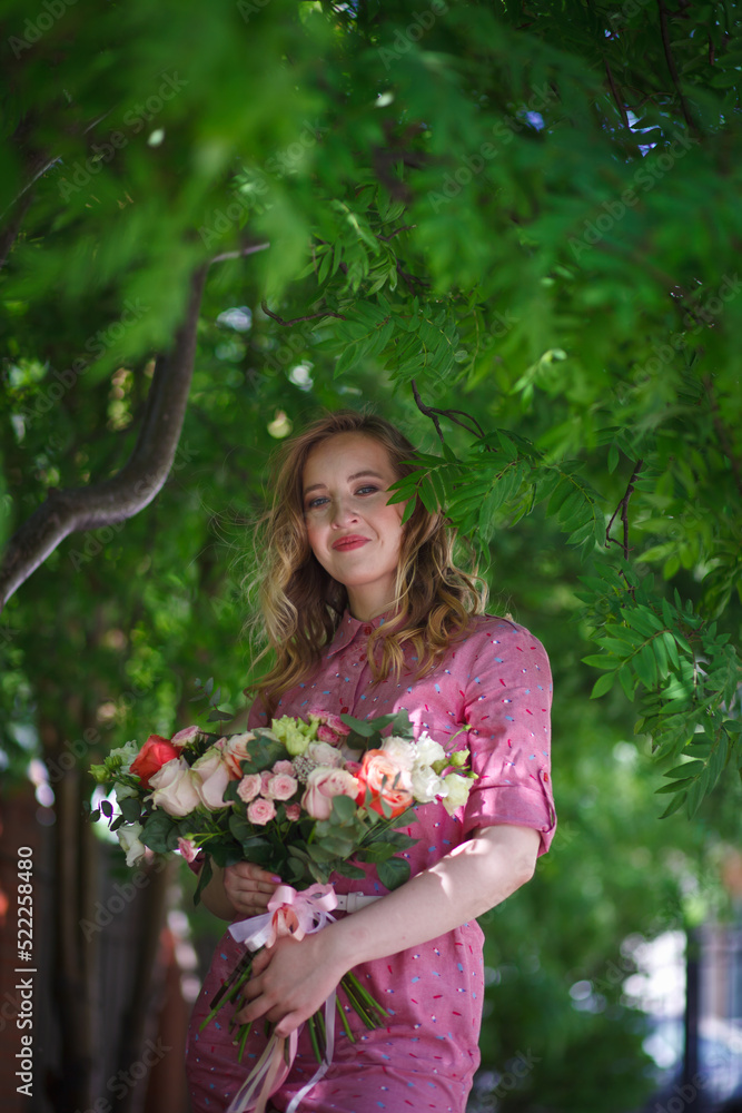 Young happy blonde woman in a pink dress with a large bouquet of flowers walks around the old European city and enjoys life on a summer day, beautiful portraits with a huge bouquet of flowers. Young happy blonde woman in a pink dress with a large bouquet of flowers walks around the old European city and enjoys life on a summer day, beautiful portraits with a huge bouquet of flowers.