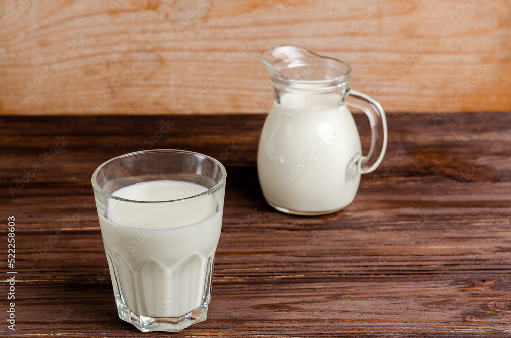 Kefir in a glass glass and decanter, fermented milk product on a wooden background Kefir in a glass glass and decanter, fermented milk product on a wooden background