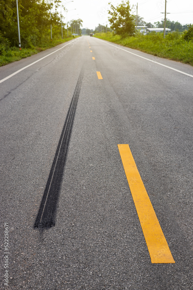 A close-up low-angle view. A long line of black rubber tires stopping violently against the paved road surface.