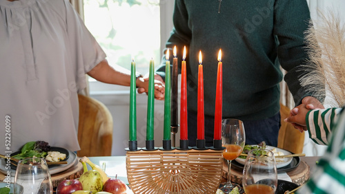 Family with daughter (12-13) holding hands over Kwanzaa meal photo