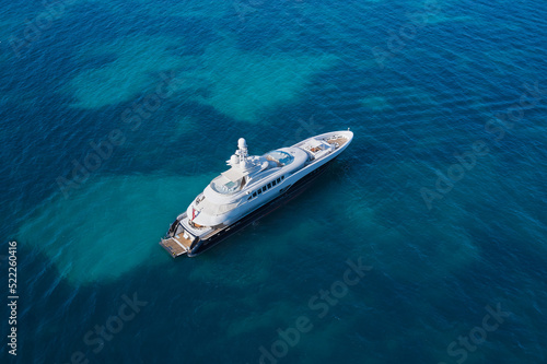 White big yacht for a billionaire anchored on a transparent aerial view. Mega yacht on blue top view. Modern big white yacht on transparent water top view. © Berg