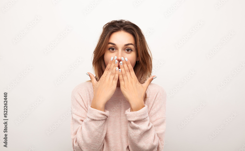 Surprised young woman covering mouth and gazing at camera Surprised young woman covering mouth and gazing at camera
