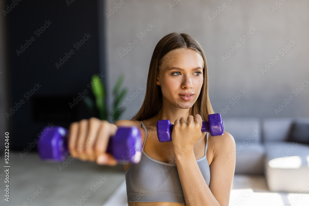 Fitness at home concept. Smiling young woman on mat make exercises with sports equipment at home.